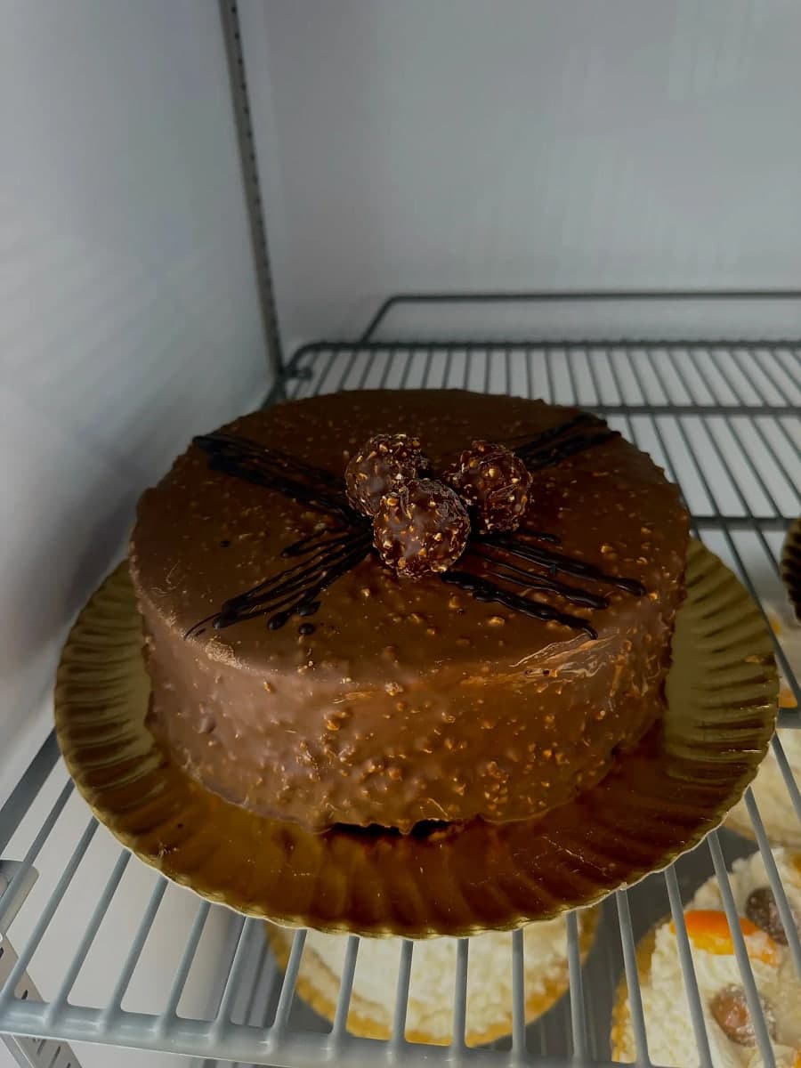 Tarta de Ferrero de Kerrico en la vitrina, bañada en crema de avellana y chocolate con tres bombones Ferrero Rocher encima.