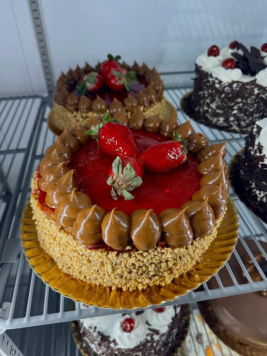 Tarta de fresas de Kerrico en la vitrina, con crema y mermelada de fresa, fresas frescas encima y un borde de crocante de nueces caramelizado.